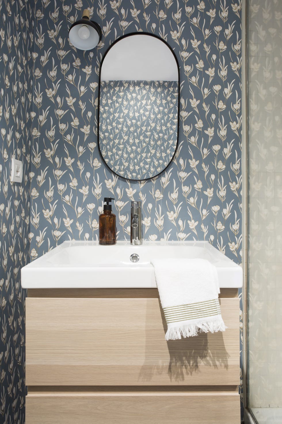 baño con mueble de madera y papel pintado azul floral