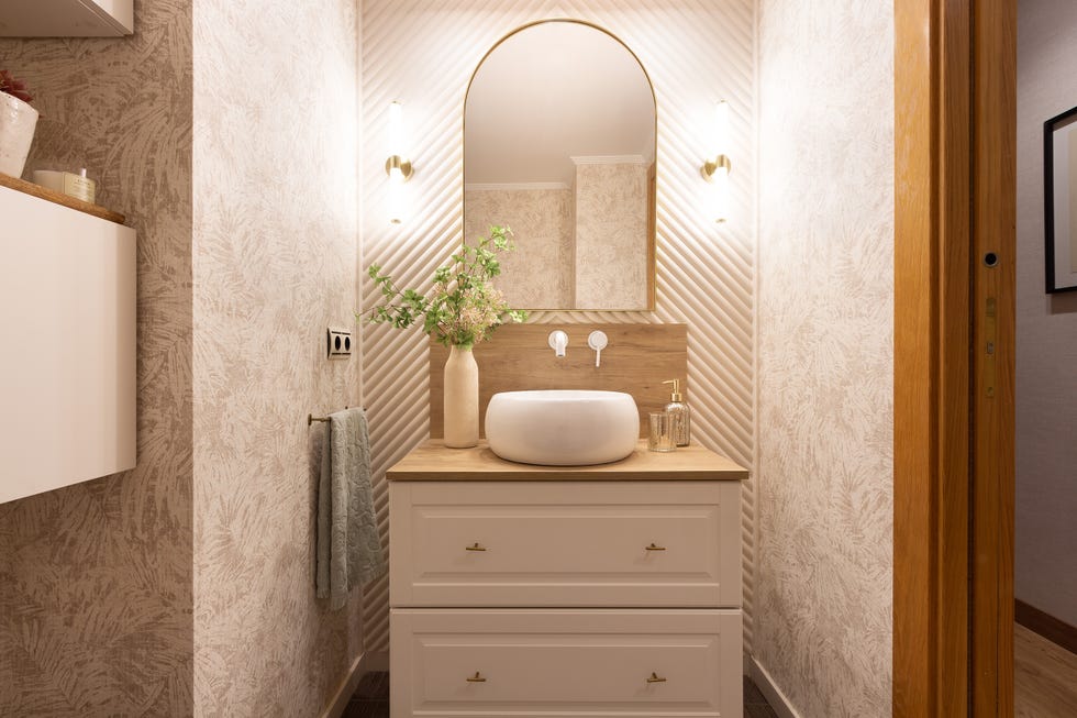 baño con mueble blanco bajolavabo y papel pintado botánico