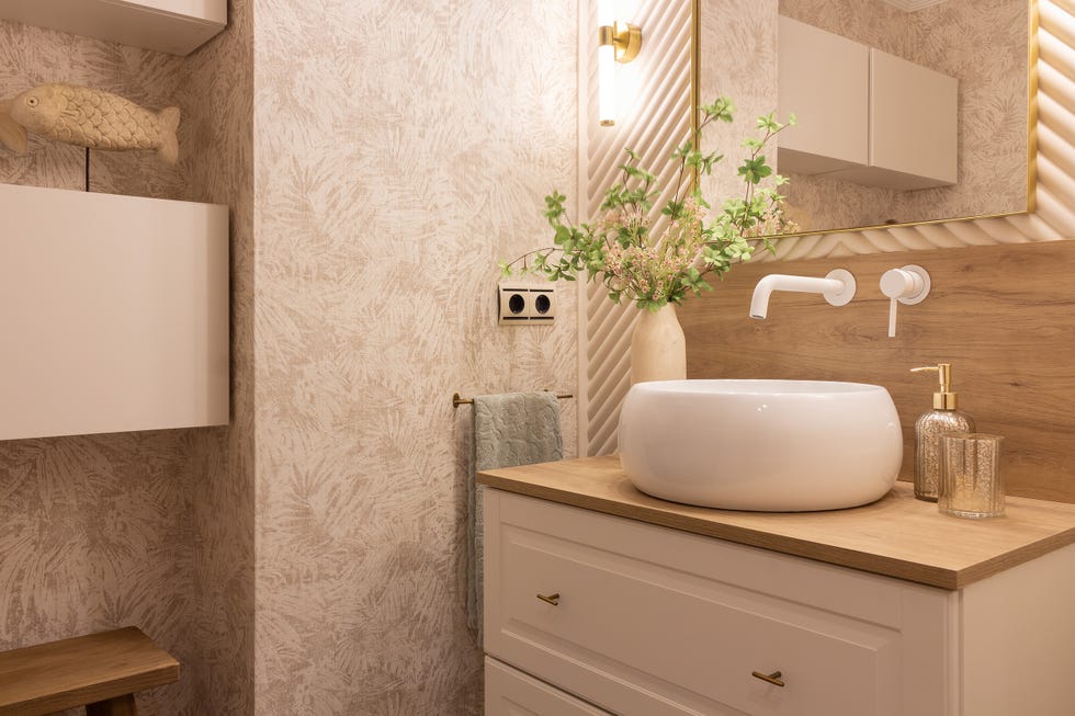 baño con mueble blanco bajolavabo y papel pintado botánico