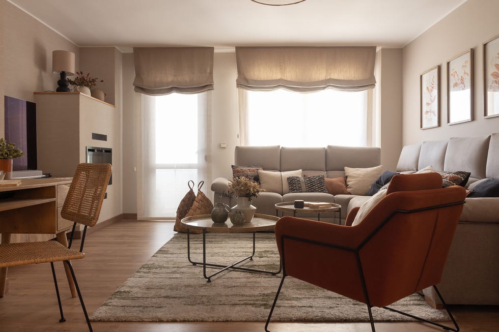 salón con sofá rinconera beige, mesas de centro redondas y butaca de terciopelo terracota