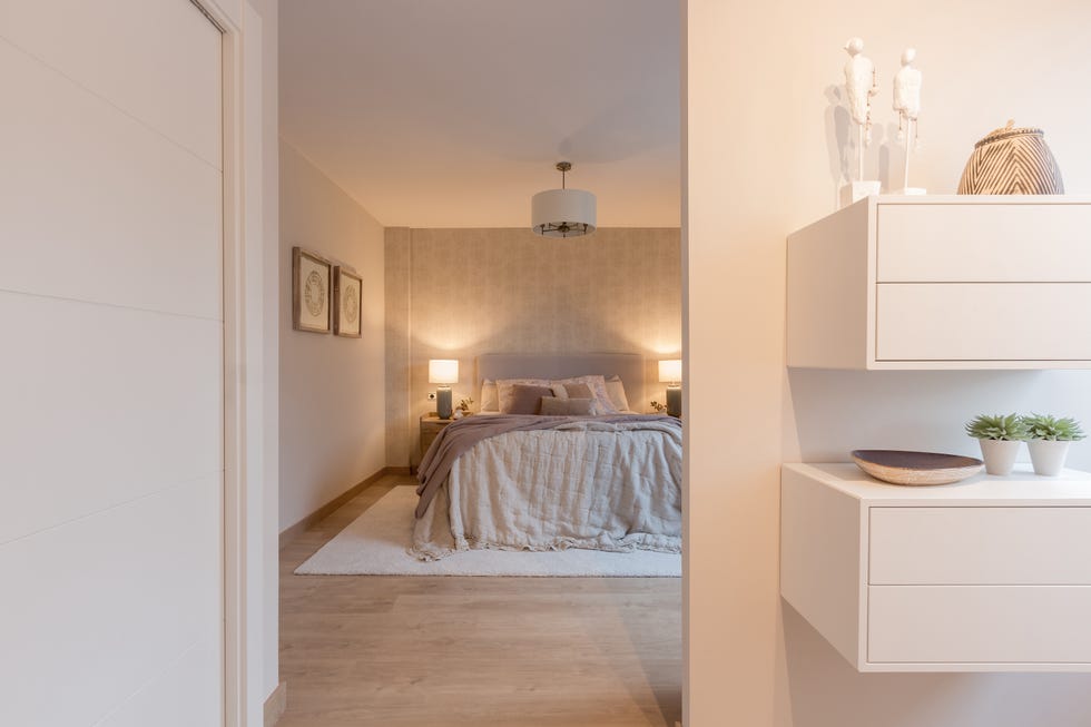 dormitorio decorado en tonos cálidos y dos estanterías de pared blancas