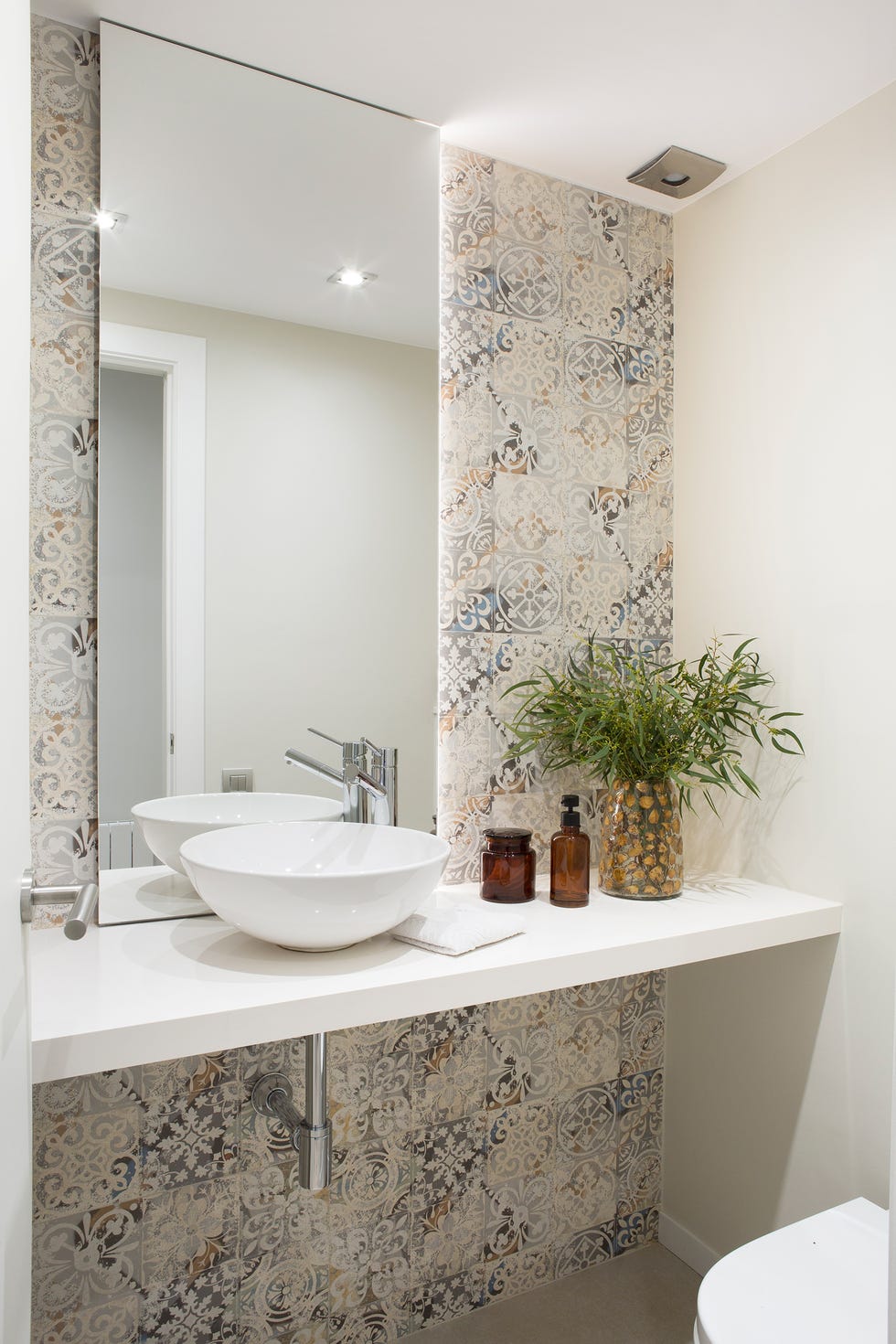 baño con encimera blanca volada y azulejos tipo hidráulicos
