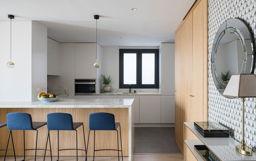 cocina abierta con península de mármol y madera y taburetes azules