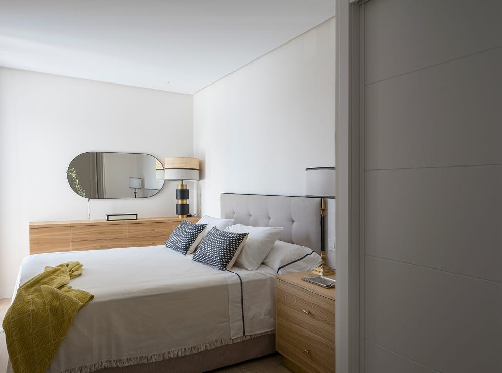 dormitorio decorado en tonos neutros con mesitas de noche y aparador de madera