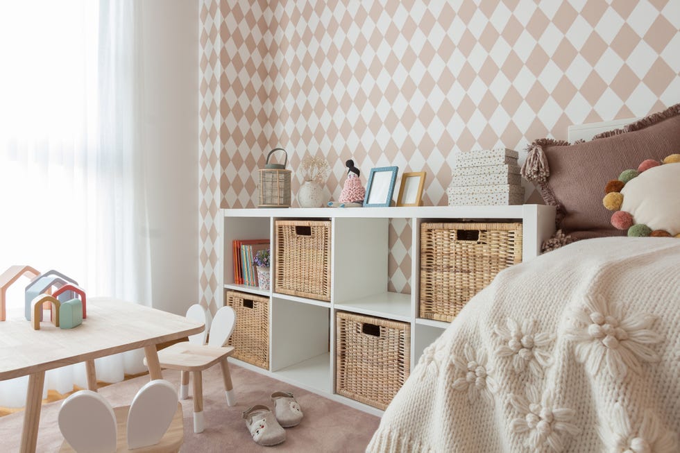habitación infantil con muebles blancos y papel pintado con rombos rosas
