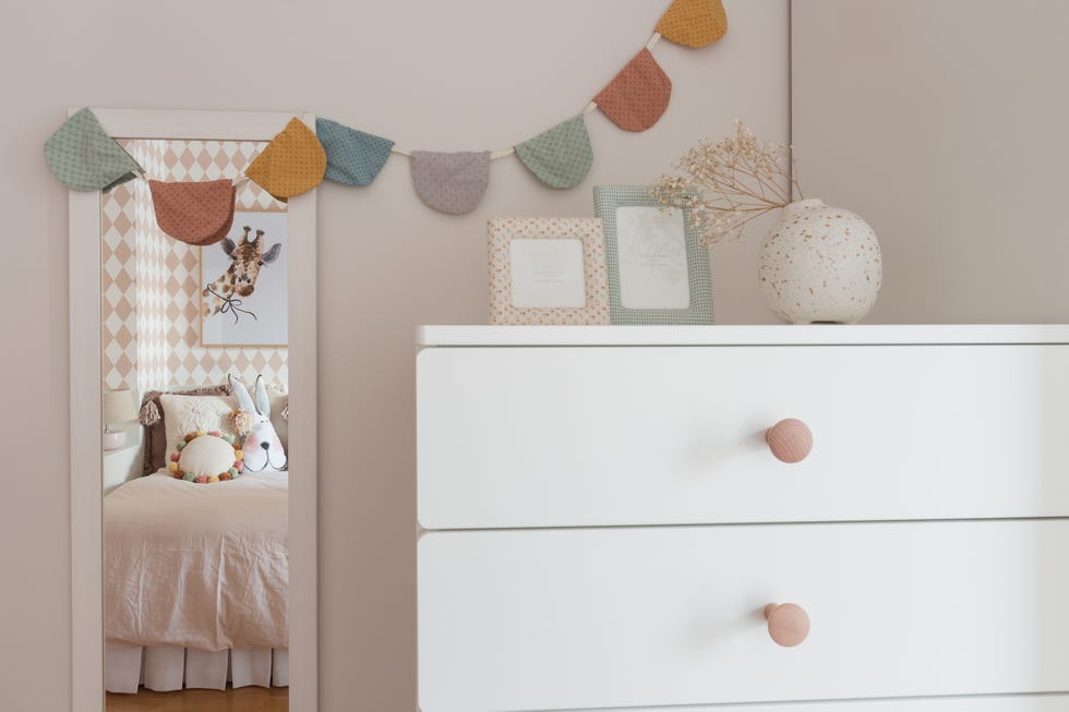 habitación infantil con muebles blancos y papel pintado con rombos rosas