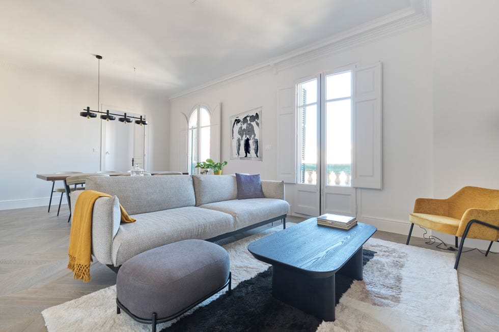salón comedor con sofá gris, puff, butaca amarilla y mesa de centro de madera