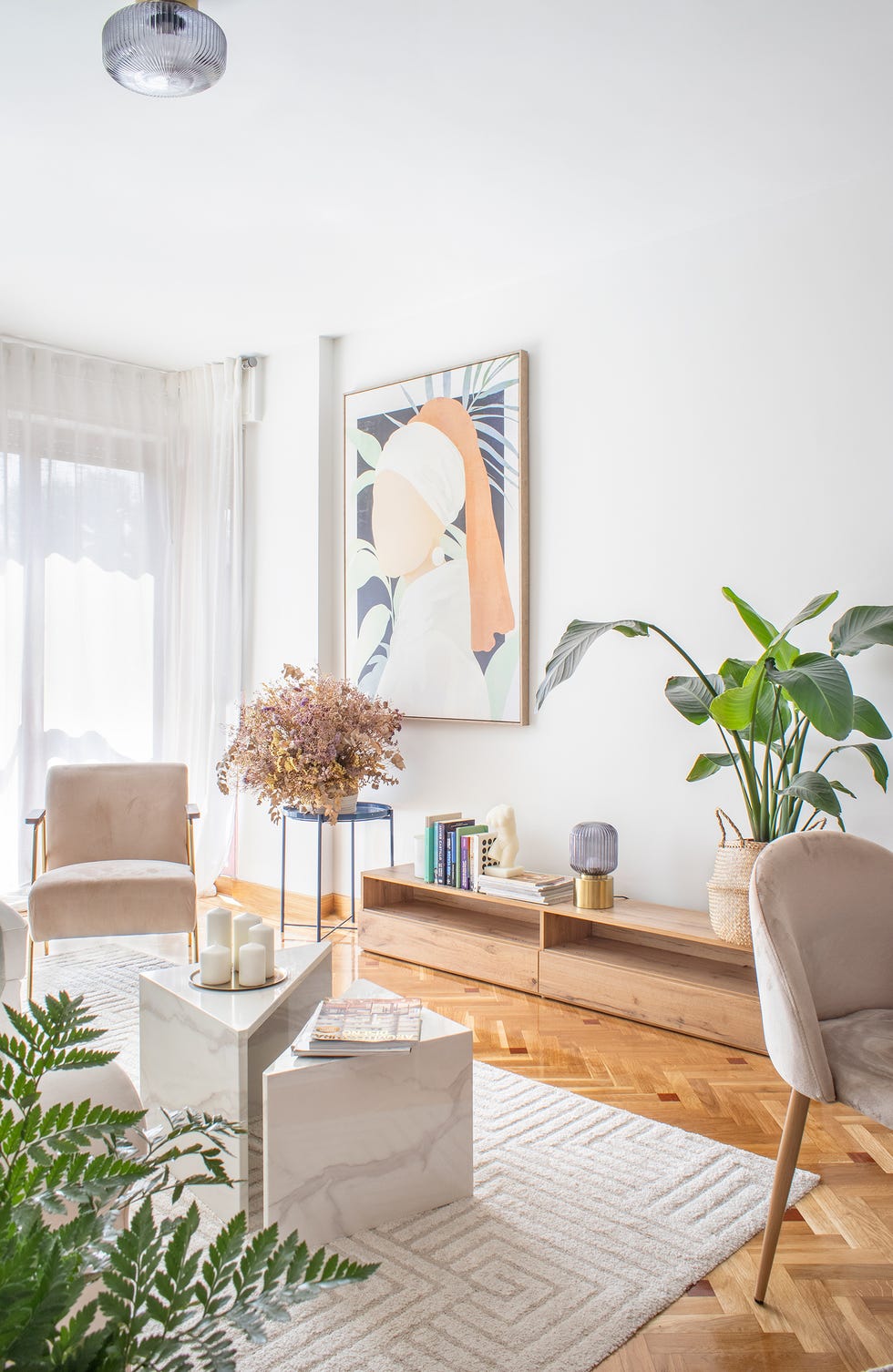 salón moderno y chic con mesas de centro de mármol, butaca de terciopelo rosa, alfombra con motivos geométricos y mueble tv de madera