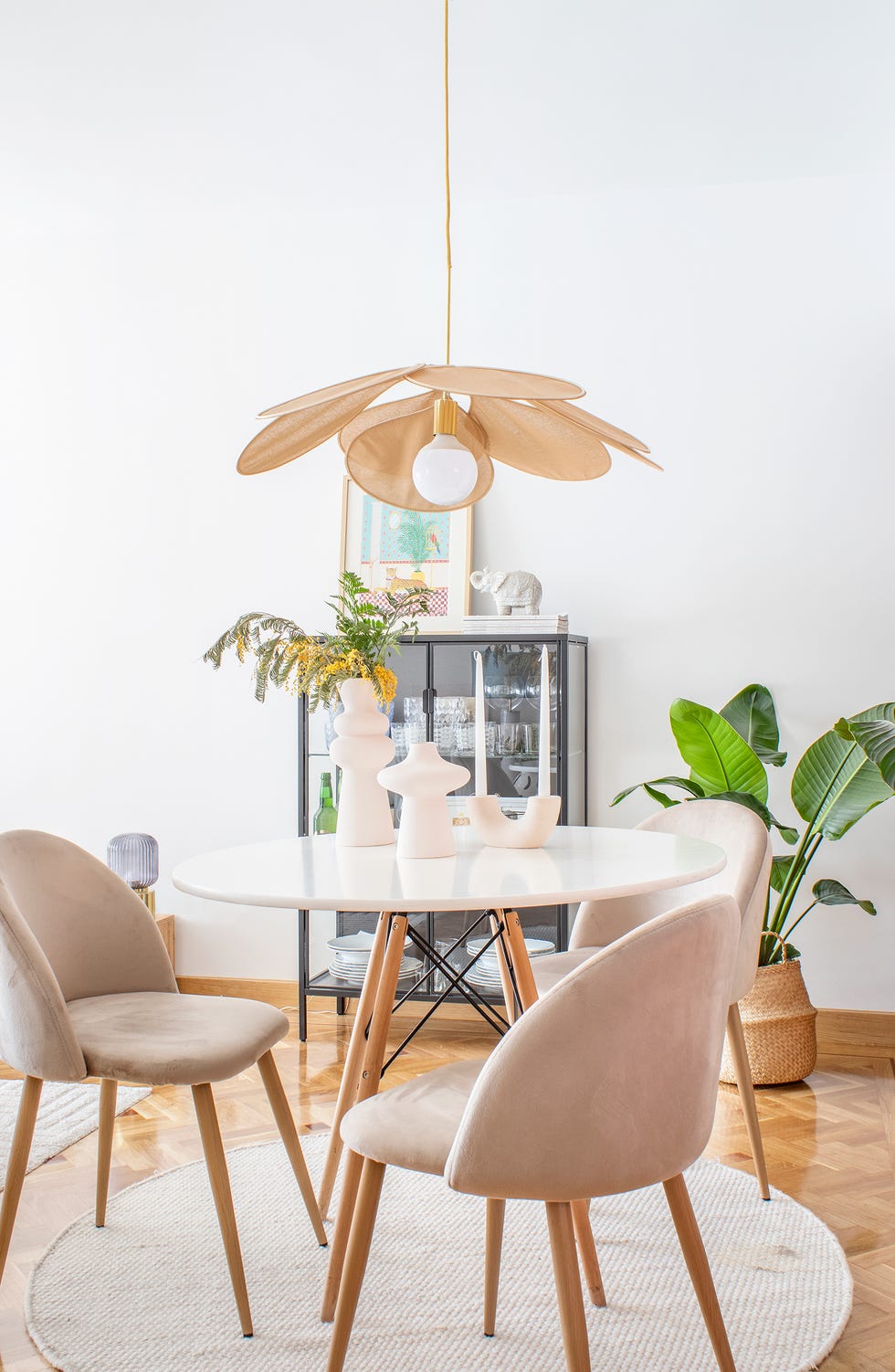 comedor con mesa nórdica redonda, sillas de terciopelo en color nude y lámpara con pétalos de ratán