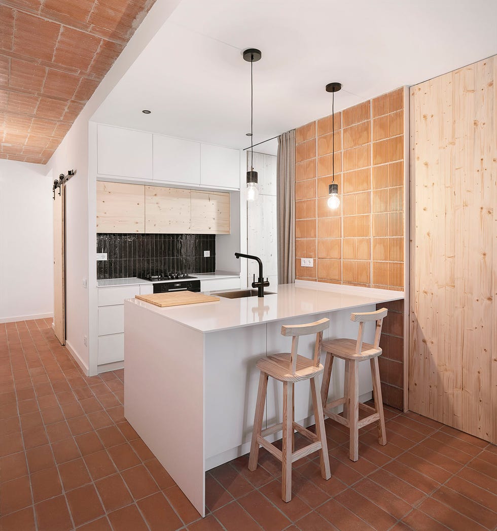 cocina con barra de color blanco y revestimientos de ladrillo visto
