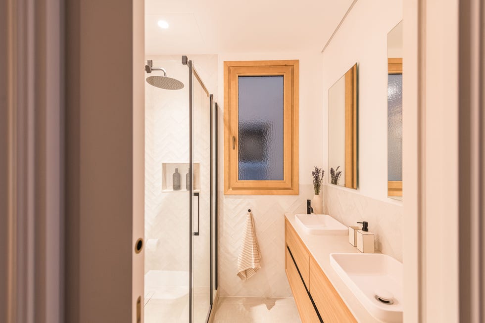 baño con azulejos blancos en espiga y mueble de madera suspendido