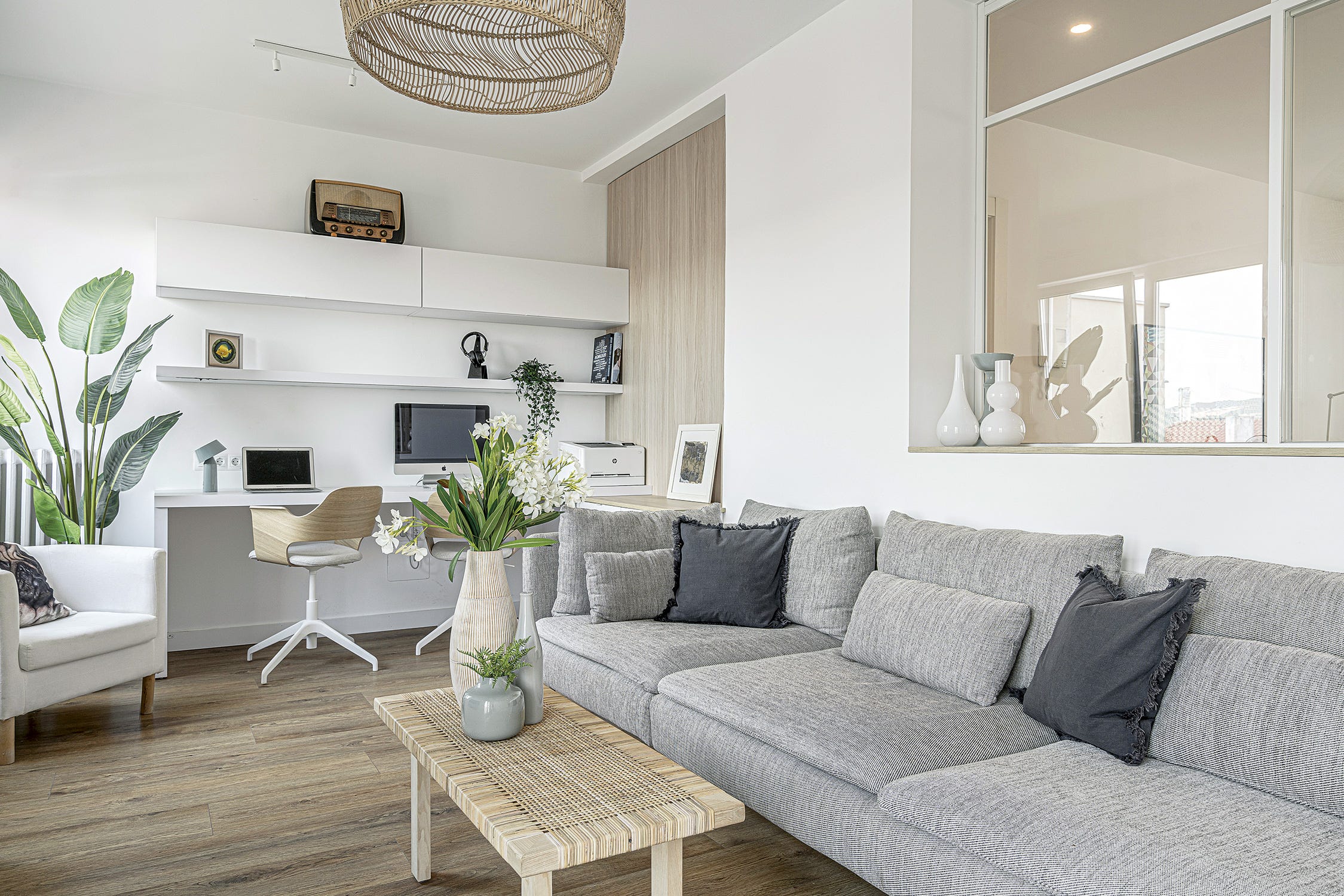 piso blanco y moderno salón con sofá gris y zona de trabajo y estudio