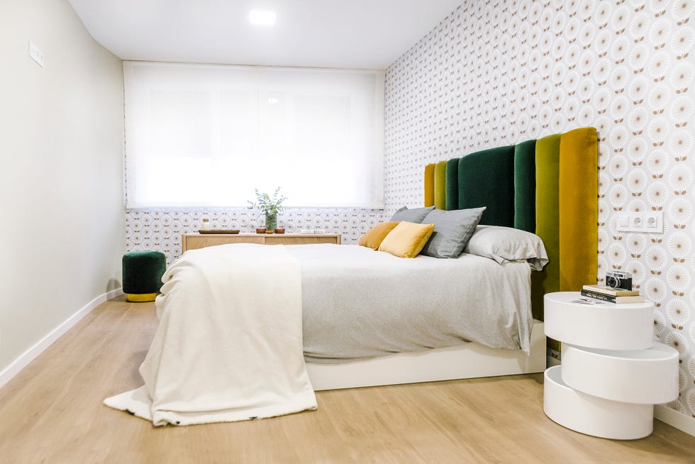 dormitorio decorado con papel pintado setentero y cabecero tapizado en terciopelo