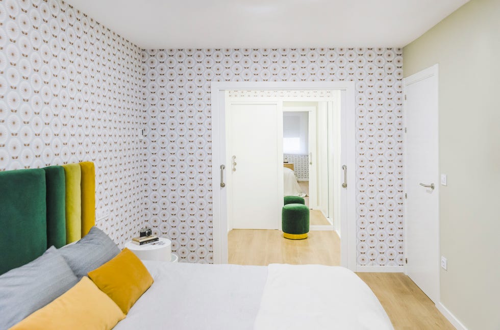 dormitorio decorado con papel pintado setentero y cabecero tapizado en terciopelo