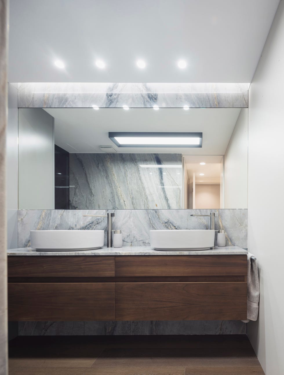 baño con mueble volado de madera y revestimiento de mármol