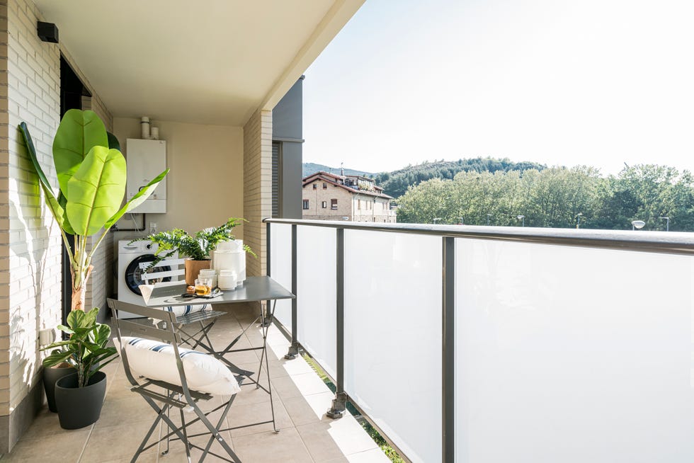 terraza decorada con plantas y una mesa con dos sillas plegables