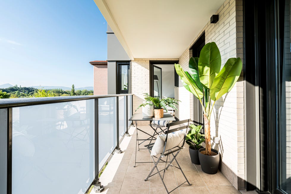 terraza decorada con plantas y una mesa con dos sillas plegables