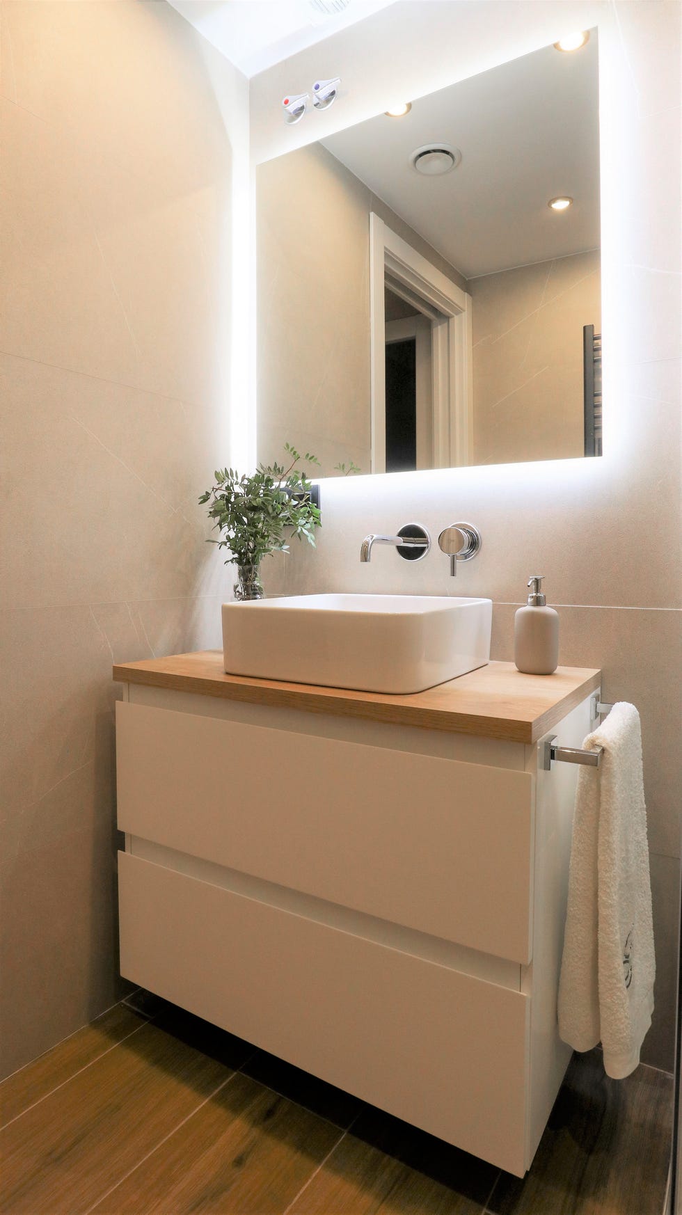 baño con mueble blanco suspendido y encimera de madera