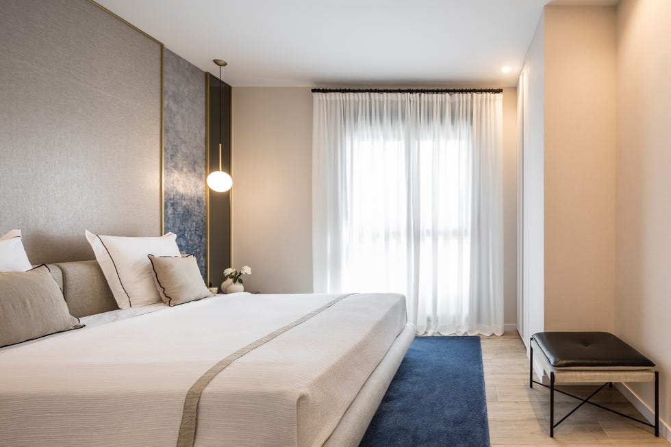 dormitorio de diseño elegante en color beige con cabecero diseñado a medida y lámparas suspendidas