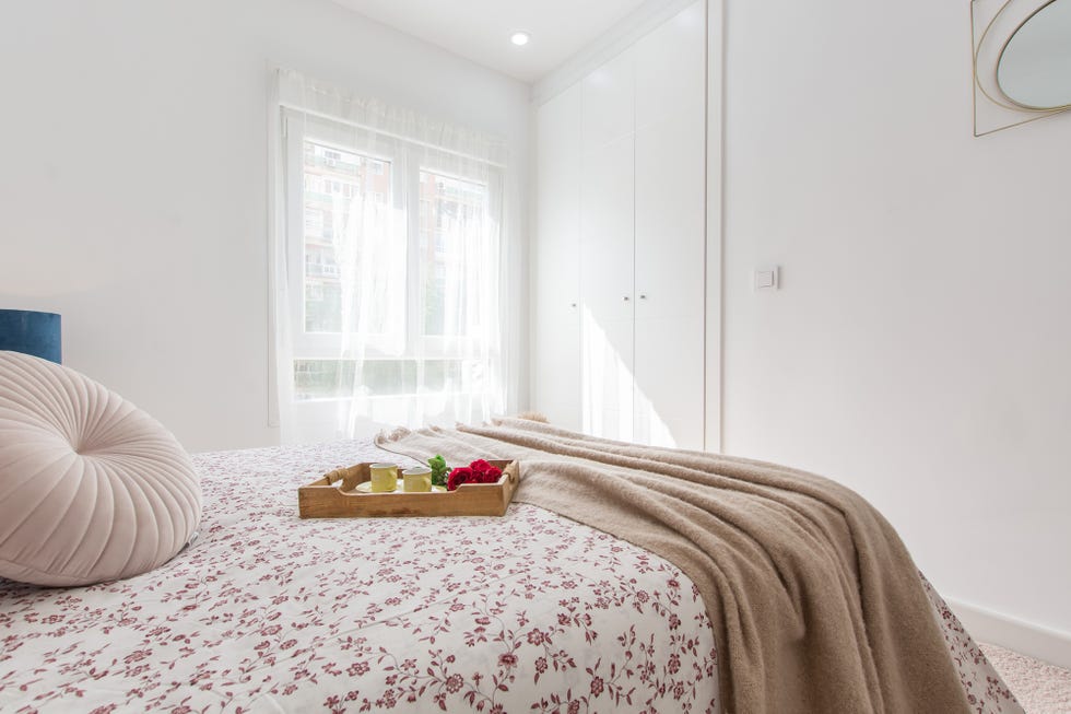 cama de matrimonio con colcha de flores y armario blanco de suelo a techo