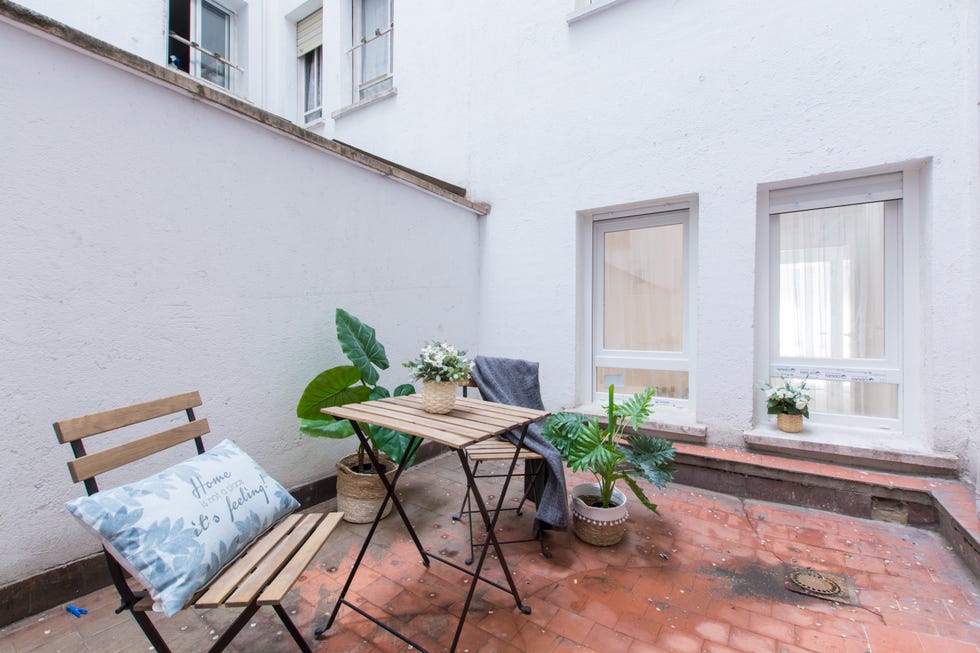 patio interior con una mesa y dos sillas plegables de madera