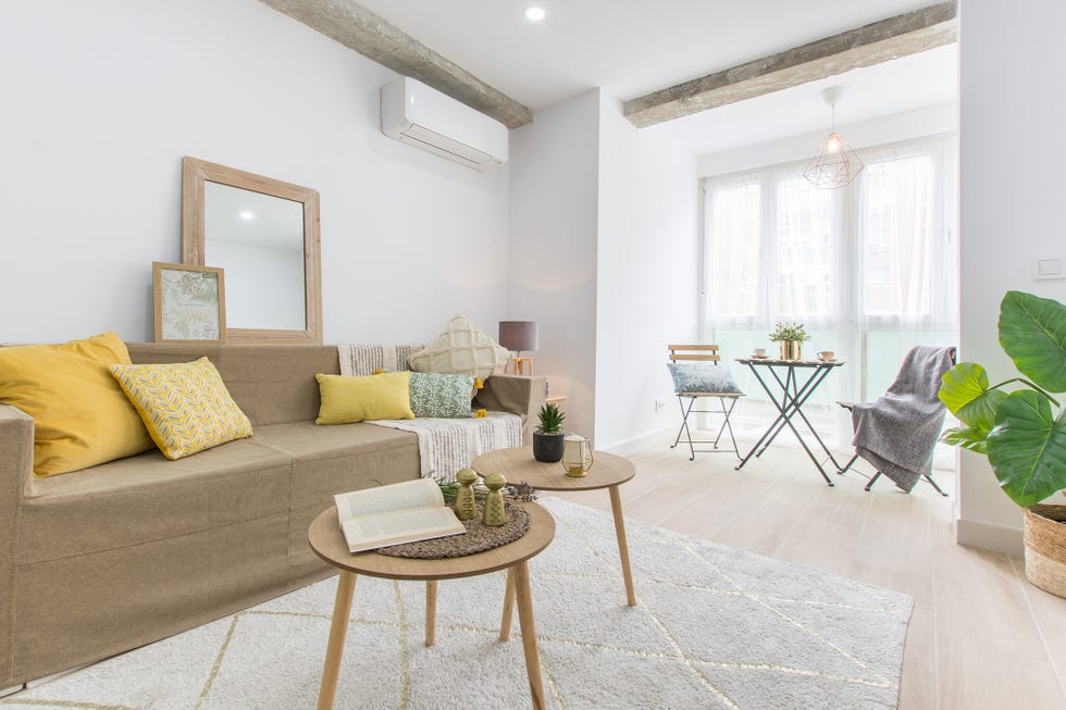 salón nórdico con sofá de tela marrón y dos mesas redondas de madera