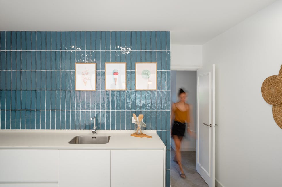 cocina con muebles blancos y azulejos azules en la pared