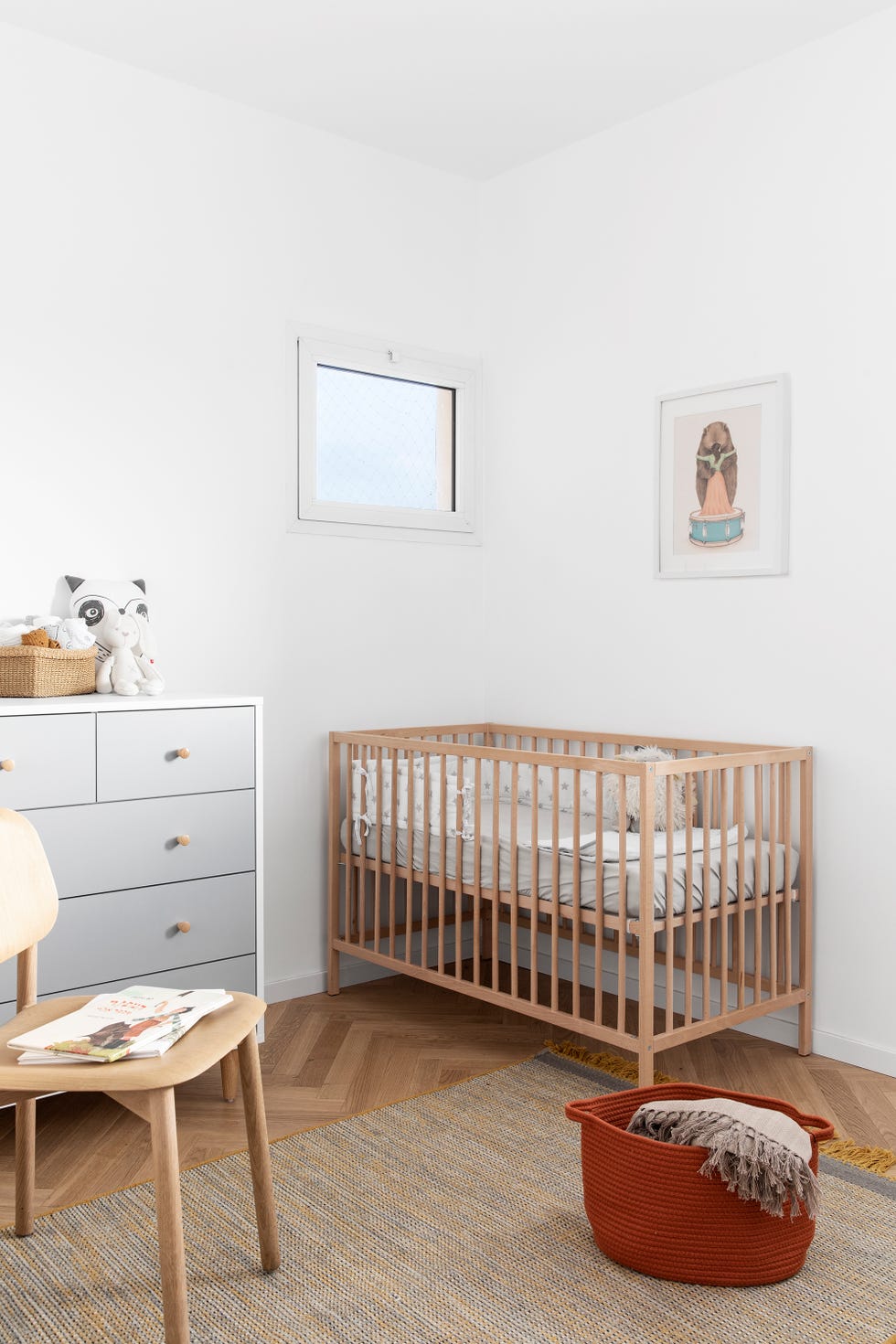 habitación de bebé con cuna de madera y cómoda gris de estilo nórdico