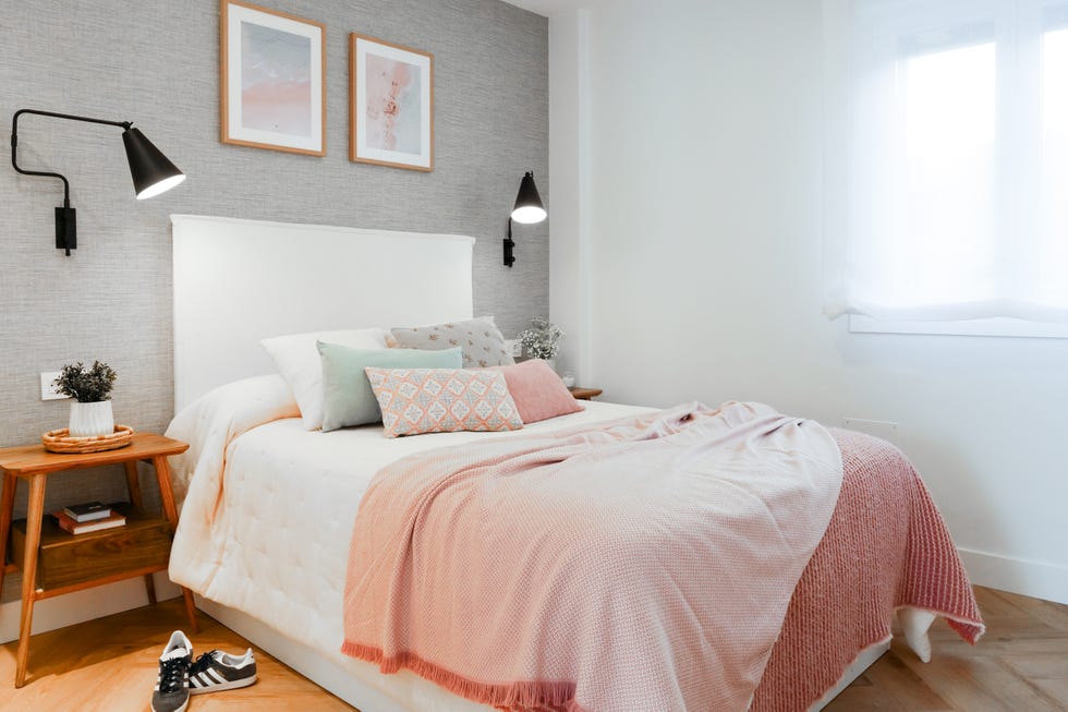dormitorio con cama con cabecero tapizado en blanco, papel pintado gris con efecto tejido y mesitas de noche de madera