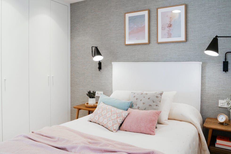 dormitorio con cama con cabecero tapizado en blanco, papel pintado gris con efecto tejido y mesitas de noche de madera