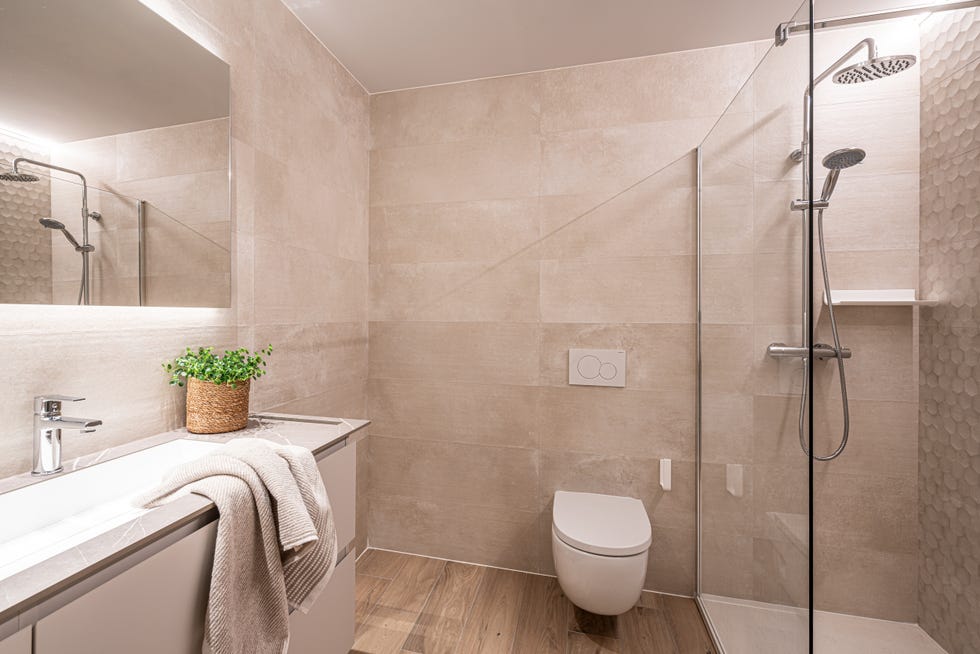 baño moderno en tonos neutros con paredes efecto piedra