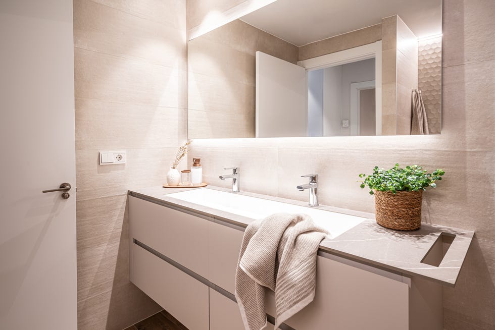 baño moderno en tonos neutros con paredes efecto piedra