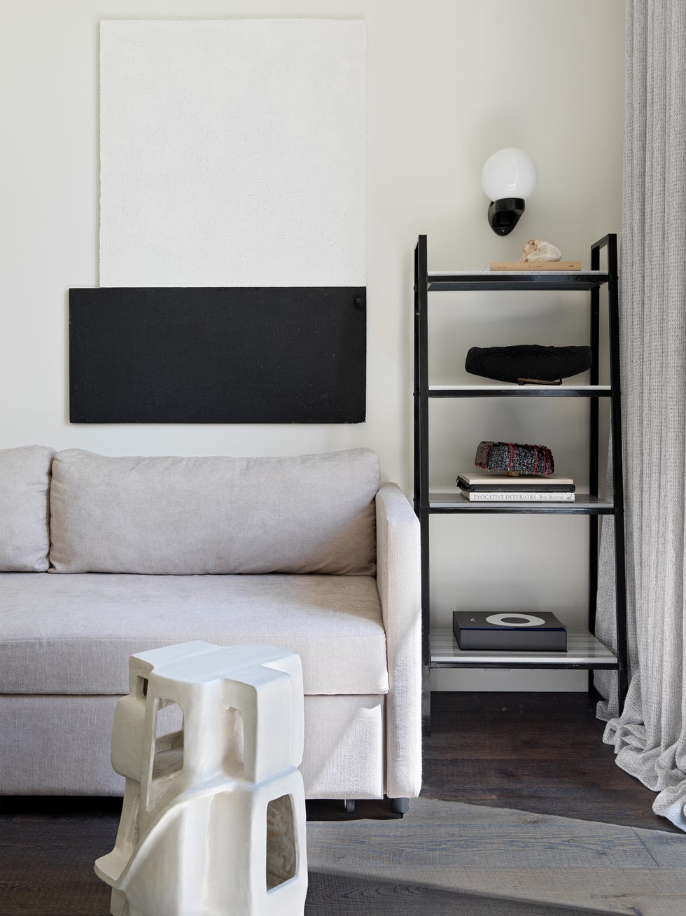 salón moderno decorado en tonos neutros con sofá gris y estantería negra metálica