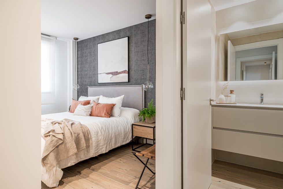 dormitorio decorado en beige y gris con cabecero de tela y lámparas suspendidas