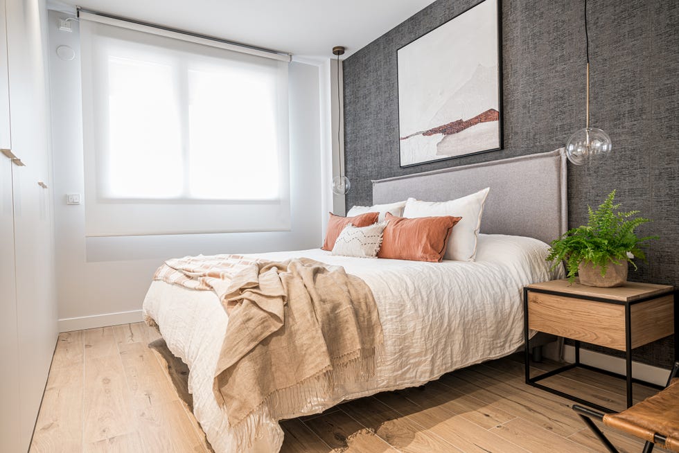 dormitorio decorado en beige y gris con cabecero de tela y lámparas suspendidas