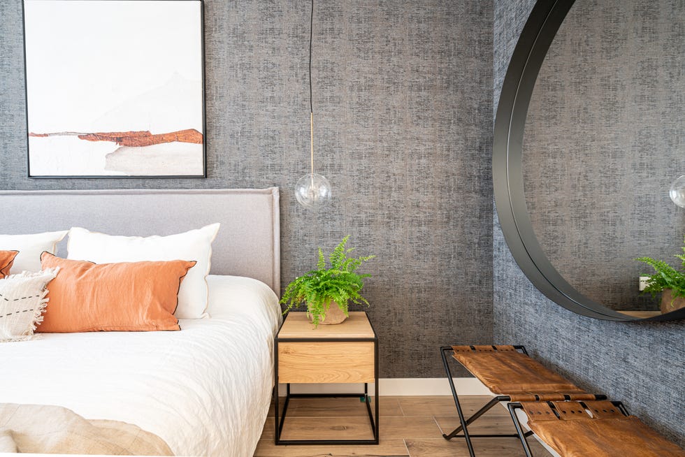 dormitorio decorado en beige y gris con cabecero de tela y lámparas suspendidas