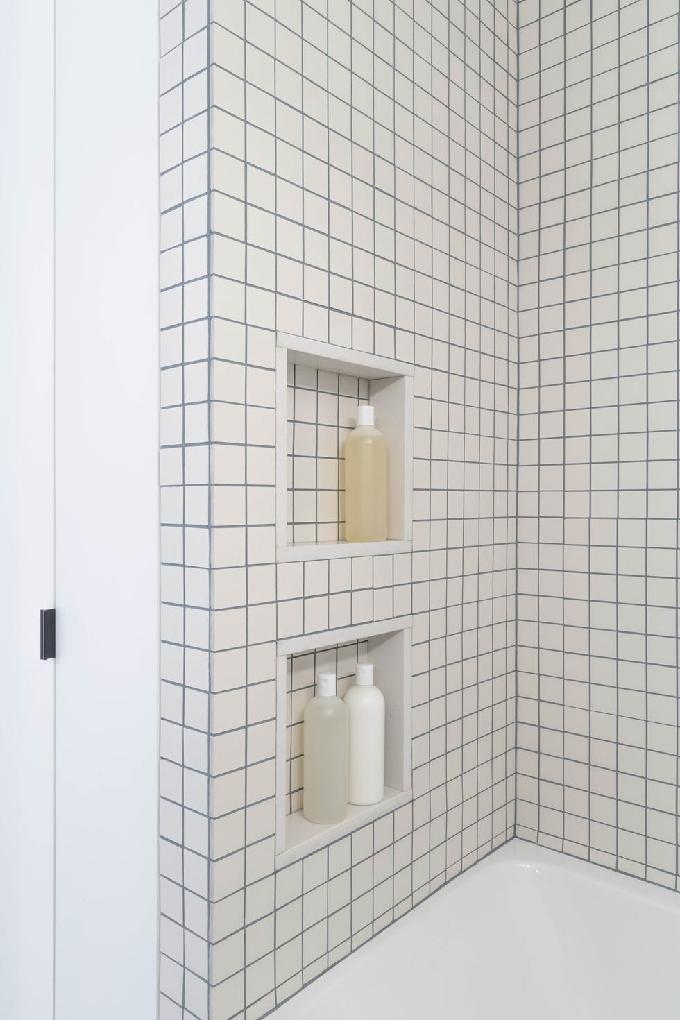 baño con bañera revestido con azulejos de cuadrícula blancos