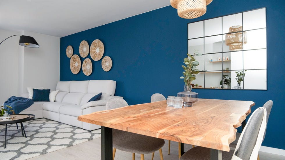 salón comedor con pared azul, mesa de madera y espejo ventana