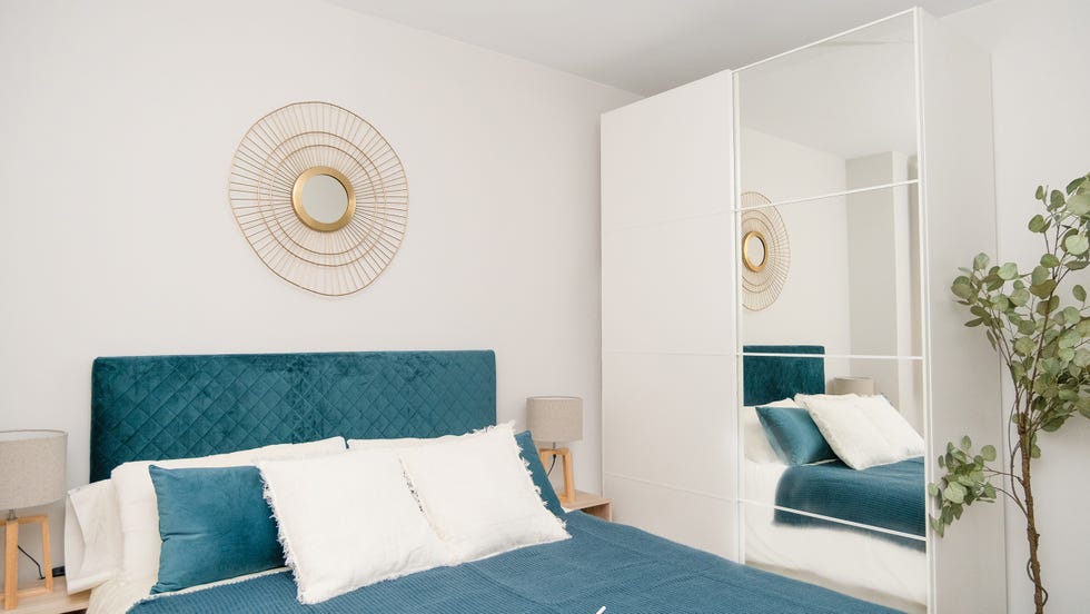 dormitorio con cabecero de terciopelo azul y armario con puertas correderas