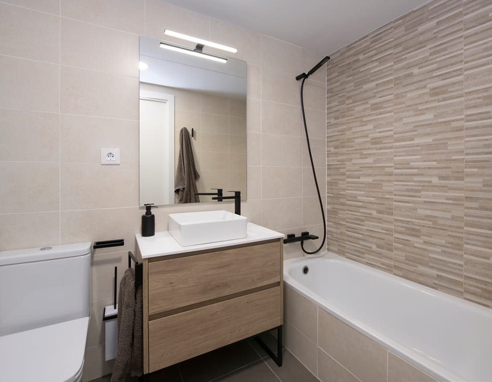 mueble bajo lavabo de madera y bañera revestida con azulejos