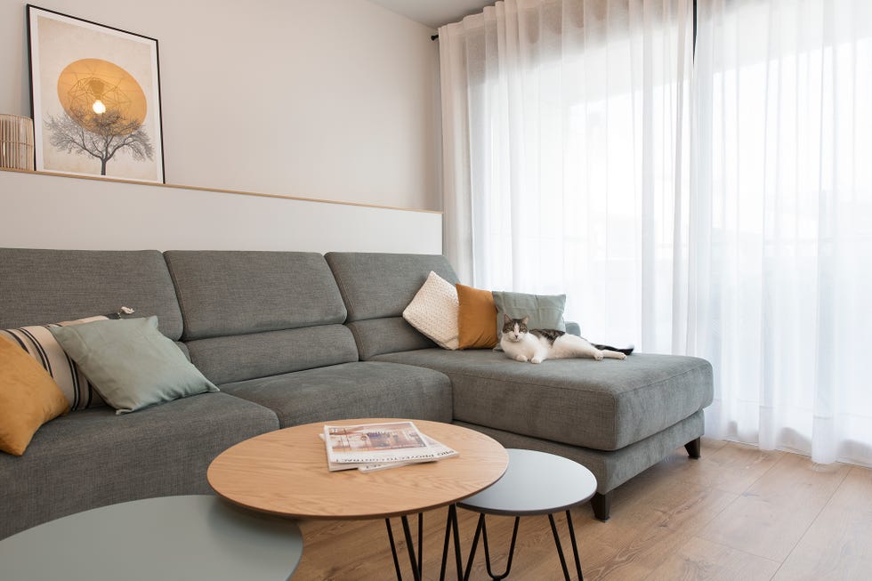 sofá con chaise longue tapizado en color gris y tres mesas de centro encastrables