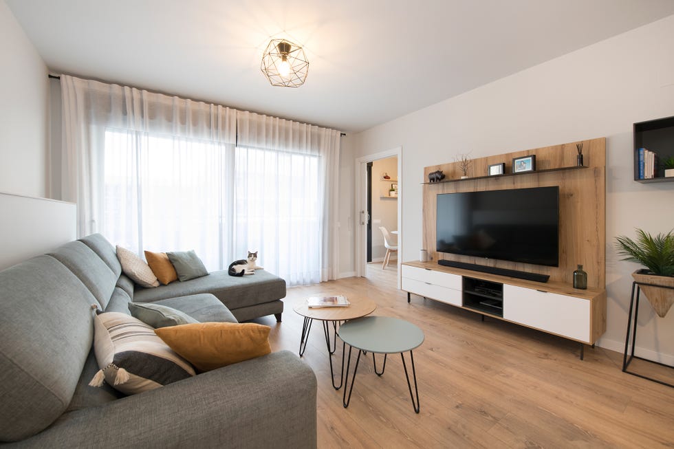 sofá con chaise longue tapizado en color gris, tres mesas de centro encastrables y mueble de tv de madera con estilo nórdico