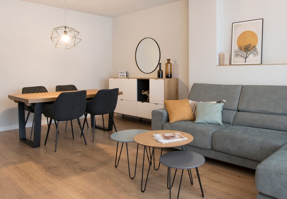 salón comedor con sofá gris, mesas encastrables, mesa de comedor de madera y sillas negras