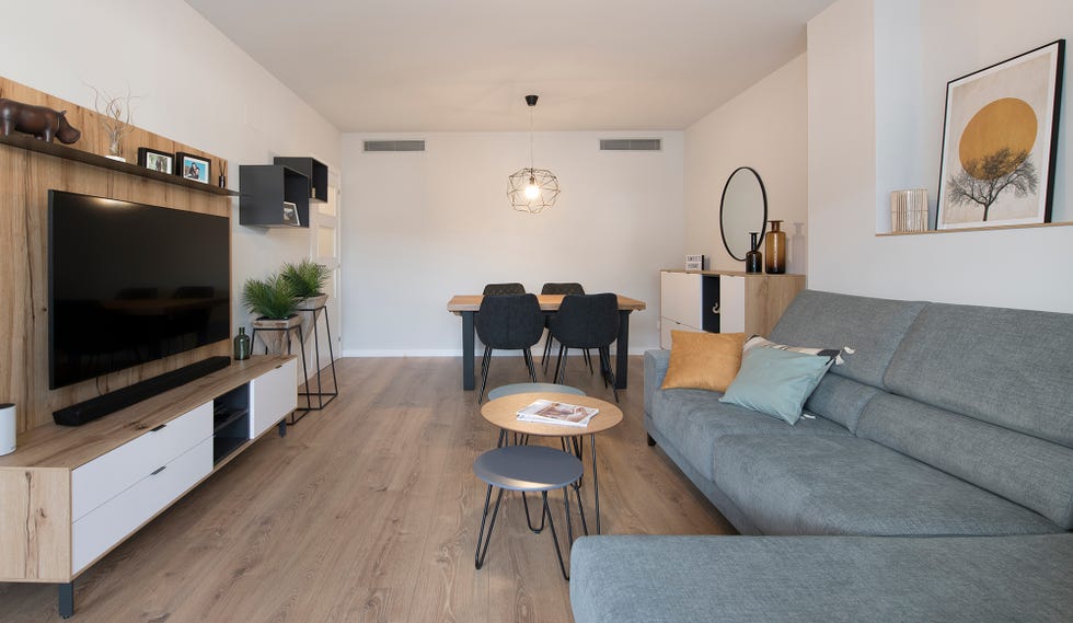 salón comedor con sofá gris, mesas encastrables, mesa de comedor de madera y sillas negras