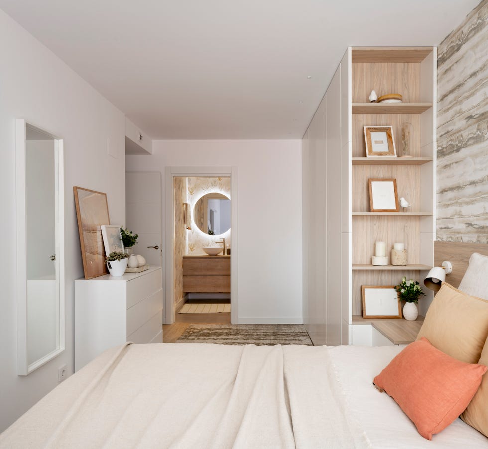 dormitorio con baño en suite y armario blanco con estantería de madera