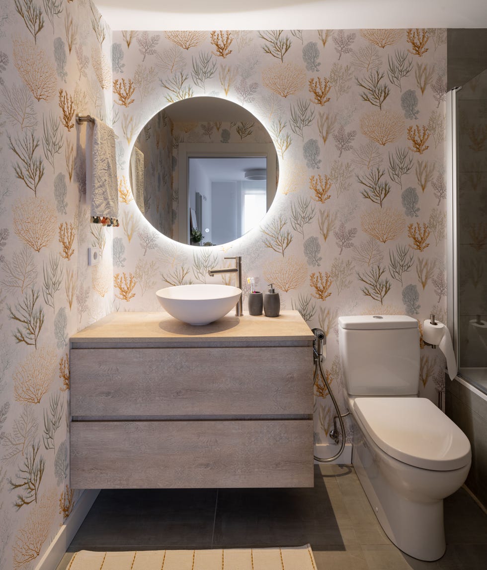 baño con mueble volado de madera y papel pintado con motivos marinos