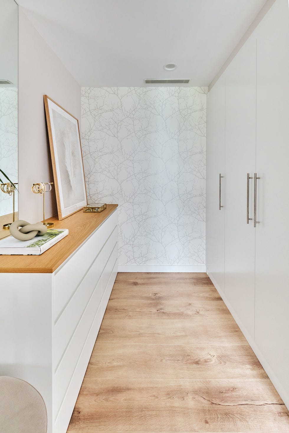 zona de vestidor con cómoda blanca y armario de pared a pared