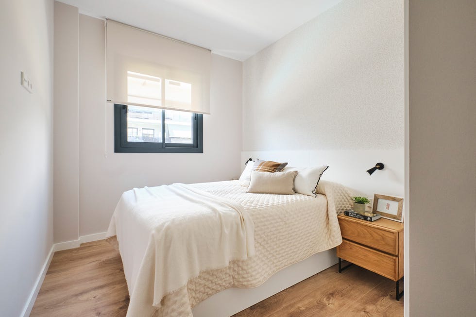 dormitorio con mesita de madera y cabecero blanco