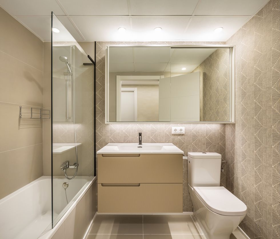 baño con azulejos geométricos, mueble de lavabo suspendido y bañera