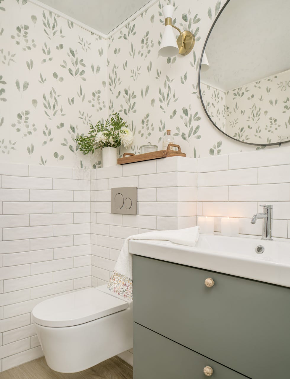 mueble de baño verde, azulejos blancos tipo metro y papel pintado con motivos botánicos